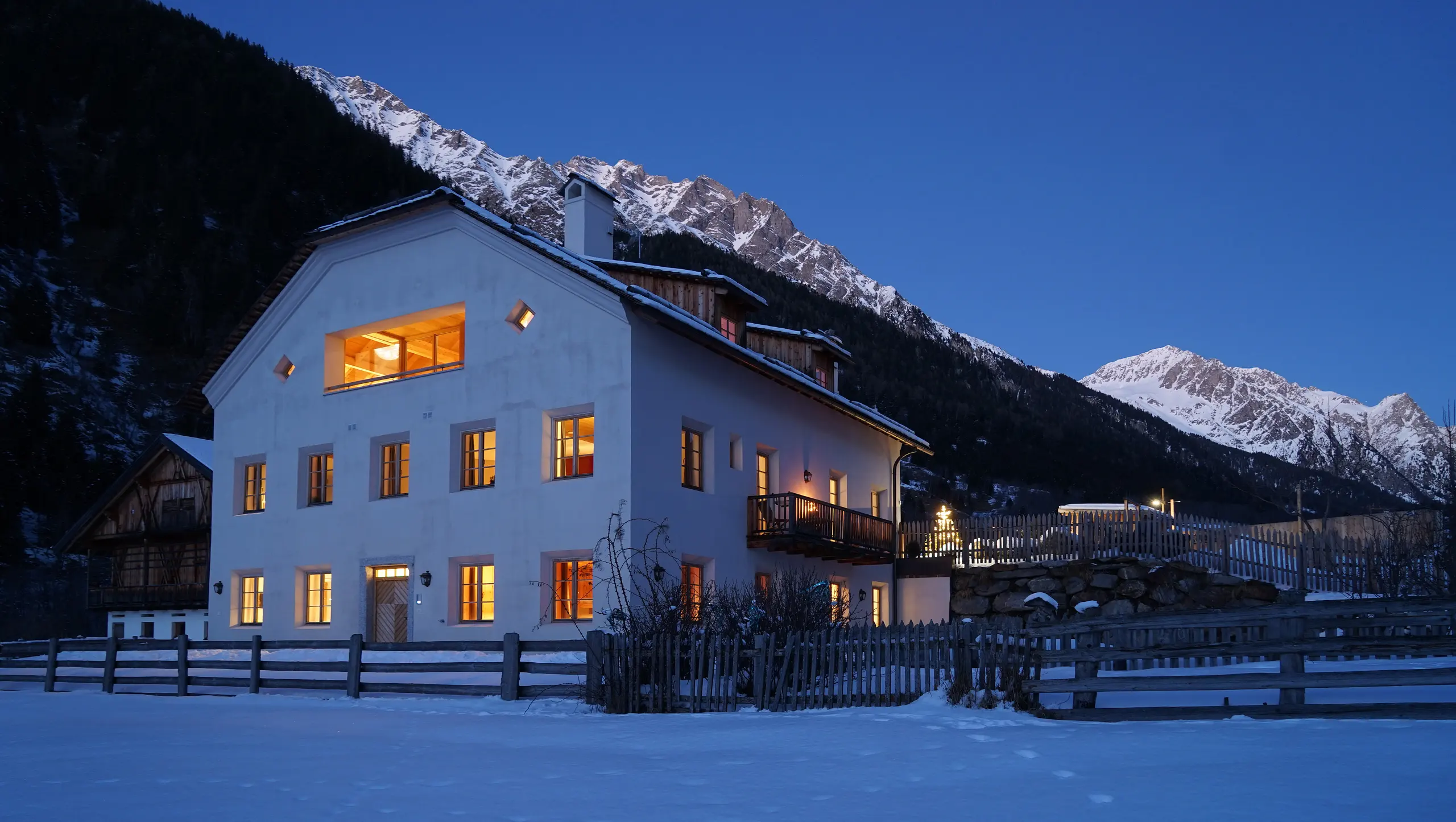 Der Halbwöhrerhof am Winterabend, warm erleuchtet